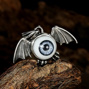 Gothic evil eye pendant with vintage silver bat wings on a natural wood surface