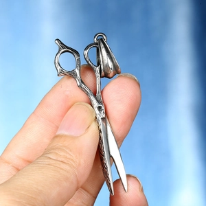 Macro detail of vintage silver scissors pendant with vine carvings and matte finish