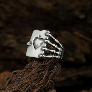 Macro detail of gothic punk ring featuring a skull hand holding an Ace of Spades card