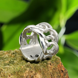 Macro shot of polished silver stainless steel woven chain ring on natural rock texture