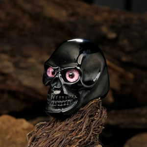 Gothic vintage black skull ring with red eye detailing on dark natural background