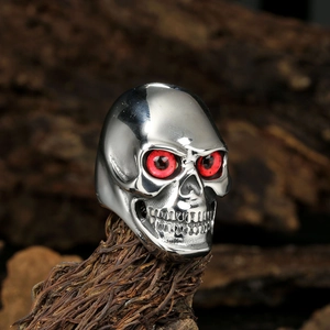 Gothic skull ring in polished silver finish with red stone eyes on dark wood bark