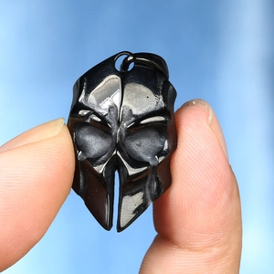 Detailed macro view of a dark gothic skull mask pendant in polished black steel