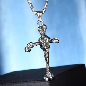 Gros plan du pendentif croix rétro avec texture d'os sur une chaîne maille vénitienne
