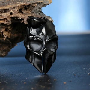 Macro shot of black Spartan helmet pendant on a piece of dark wood background