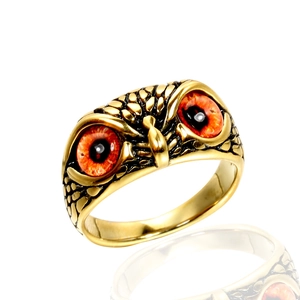 Dettaglio anello gufo con texture piume dorate e vivaci occhi rosso-arancio