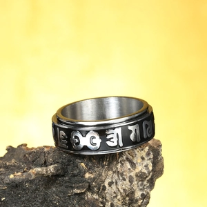 Macro detail of rotating stainless steel mantra ring on rustic bark with yellow background