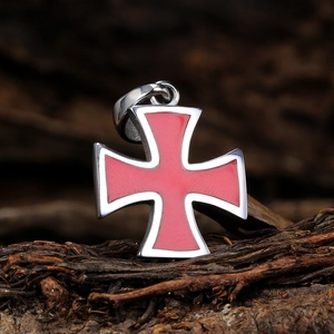 Detailed close-up of a vintage red enamel iron cross pendant on a rustic wood background