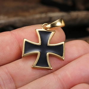 Macro shot of gold and black steel iron cross pendant held by hand for scale