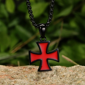 Detailed macro view of retro black Maltese cross pendant with red enamel heart on rock