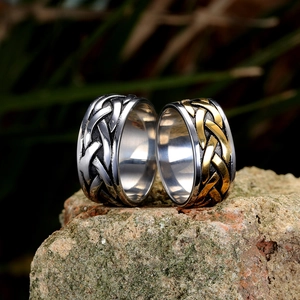 Gros plan de bagues en acier avec motif tressé viking sur une pierre naturelle moussue