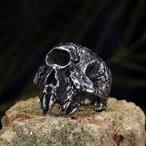 Primer plano de anillo de calavera vintage con colmillos en roca, joya gótica de acero