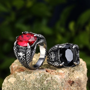 Vintage dragon claw rings with red and black gemstones set on rugged natural rock surface