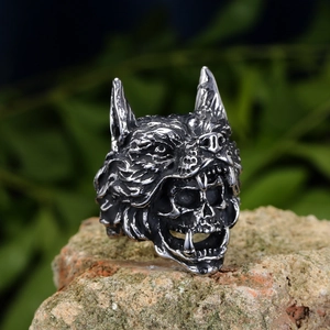 Macro shot of a gothic wolf head and skull ring on a textured red mineral stone
