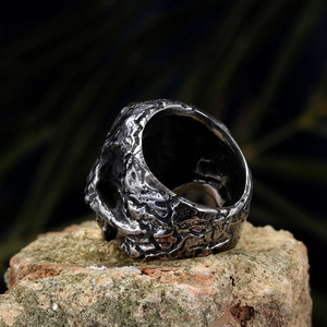 Vista macro del anillo gótico de acero de titanio con textura de lava sobre piedra mineral
