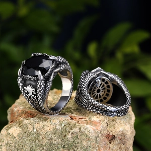 Gothic dragon claw ring with black gemstone and detailed scale texture on a natural stone