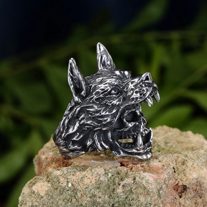 Detail of gothic wolf head ring with skull inside, placed on a natural mossy stone