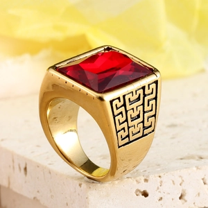 Détail d'une bague en acier doré avec pierre de rubis rectangulaire et motif de grecque