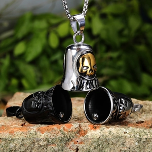 Macro shot of skull embossed bell pendants in silver and gold steel on a brick surface