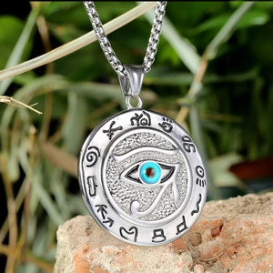 Macro shot of vintage Eye of Horus pendant on stone with Egyptian hieroglyphs
