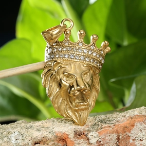 Close-up of golden lion head pendant with iced-out crown on a rustic brick background
