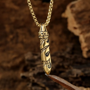 Vintage gold stainless steel necklace with engraved cylindrical pendant on a wooden background