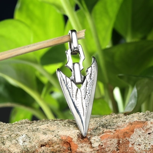 Retro arrow head pendant for men made of silver titanium steel on a natural rock background