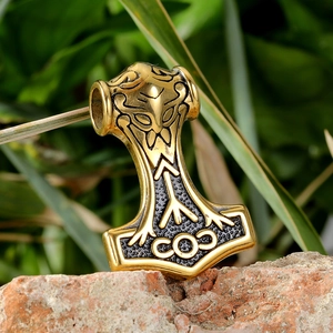 Détail du pendentif Marteau de Thor doré avec gravures vikings sur un rocher brut