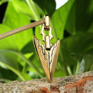 Macro detail of antique gold arrow pendant with textured finish and durable hanging loop