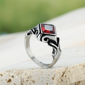 Détail macro d'une bague argentée vintage avec pierre rouge sur un support rocheux