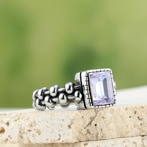 Macro-opname van een vintage ring met rechthoekige lavendelsteen en kralenband