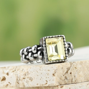 Macro-opname van vintage ring met gele rechthoekige edelsteen en gevlochten textuurband