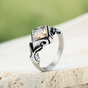 Détail macro d'une bague argentée vintage avec pierre carrée marron et gravure florale