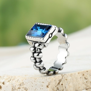 Detailopname van een vintage ring met vierkante blauwe edelsteen en tandwieltextuur