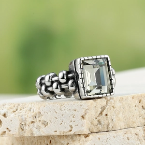 Macro-detail van retro ring met smaragdgeslepen steen en geweven getextureerde band