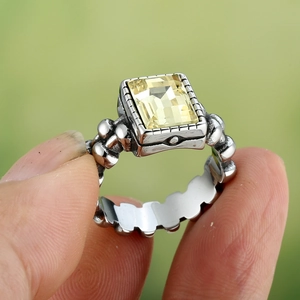 Macrodetail van vintage zilveren ring met rechthoekige gele edelsteen en kralenband