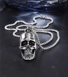 Detailed macro view of punk silver skull pendant with black crystal eyes and box chain