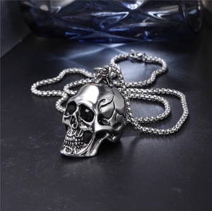 Detailed close-up of a punk style stainless steel skull pendant with black eyes