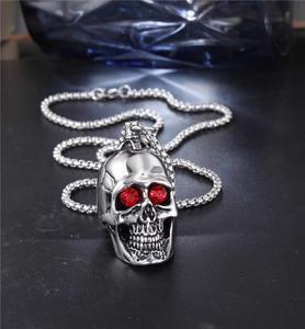 Detailed view of silver skull pendant with striking red gemstones on a metal box chain