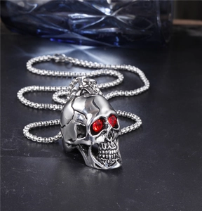 Close-up of punk skull pendant with red gemstone eyes on a steel box chain necklace