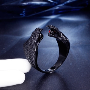 Detail van een zwart vergulde ring met dubbele slangenkop en rode edelstenen