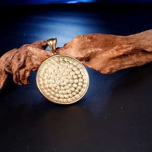 Vue détaillée d'un pendentif rond doré avec relief floral sur bois naturel texturé