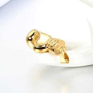 Detailed macro view of high-polished gold boxing glove pendant on white ceramic display