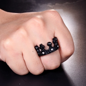 Détail d'une bague couronne noire avec croix et zircons blancs sur une main
