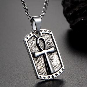 Macro detail of silver titanium Ankh cross pendant with star engraving on square link chain
