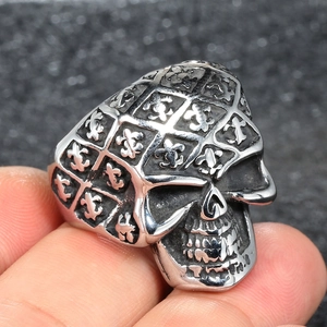 Macro detail of vintage skull ring featuring fleur-de-lis engravings on polished steel