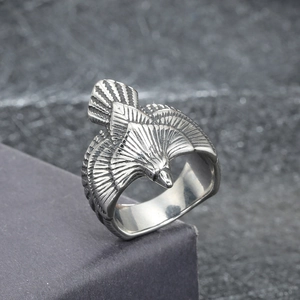 Macro shot of a vintage eagle ring with detailed feathers on a textured dark background