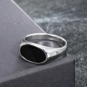 Macro shot of silver stainless steel signet ring with oval black drip oil inlay