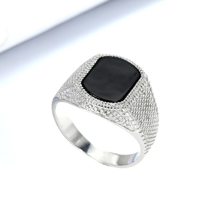 Macro side view of men's silver ring with black gemstone and textured grid engraving