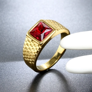 Macro shot of men's vintage gold ring with square red gemstone and grid texture